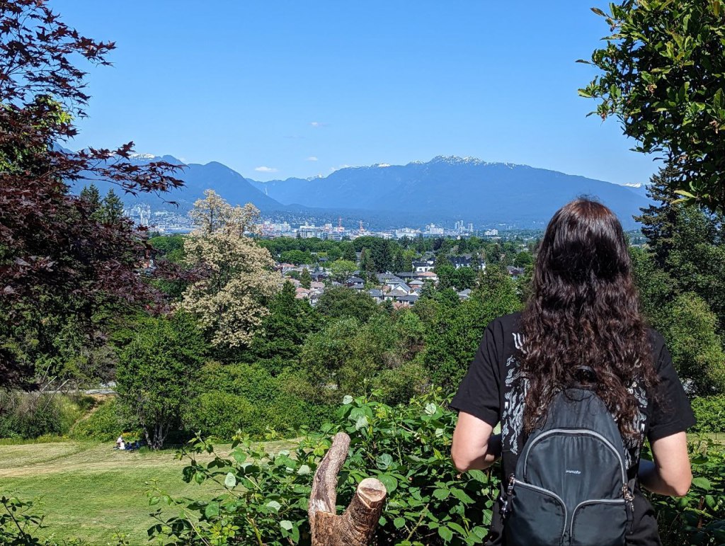 Picture of myself standing on the top of Little Mountain at Queen Elizabeth Park looking at the mountains and the skyline of Vancouver.