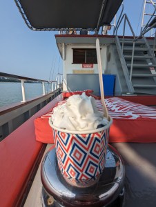 Ein Becher mit Blaubeeren und Sahne steht auf dem silbernen Nubbel, an dem man eines der Anlegeseile des Bootes befestigt.