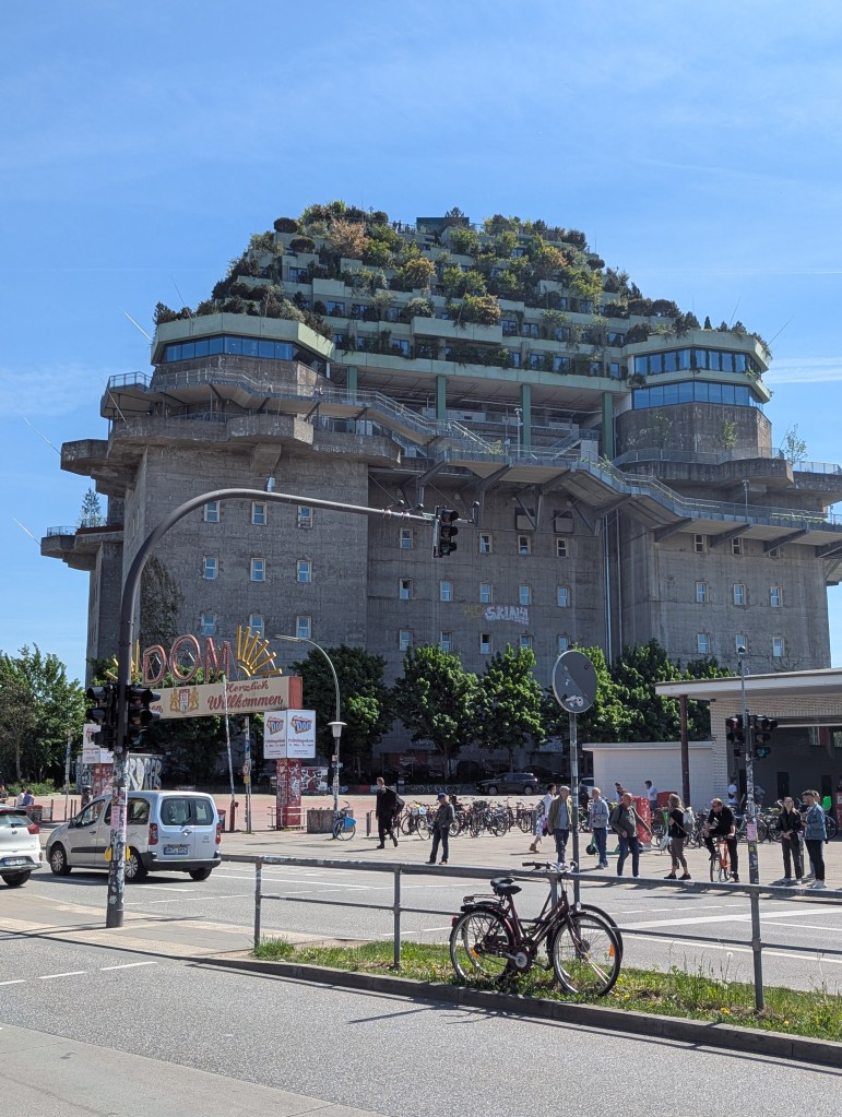 Ein Hochbunker, der im oberen Teil viele Bäume und Büsche hat.