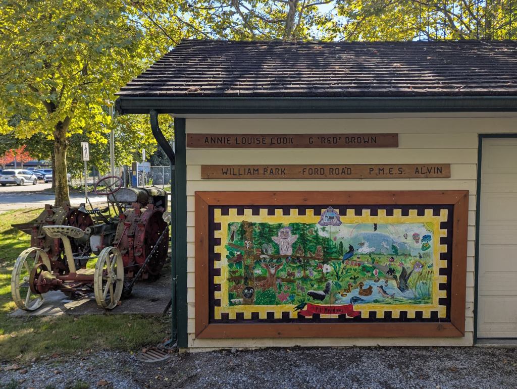 An der Wand eines Hauses ist eine, wahrscheinlich von Kindern, gemalte Szene aus Pitt Meadows angebracht. Zu sehen sind ein See, eine Wiese, Bäume, ein Berg im Hintergrund und viele Tiere wie eine Eule, Eichhörnchen, Vögel, ein Reh, Gänse und viele mehr. Neben dem Haus steht ein altertümlicher, etwas verrosteter, Traktor.