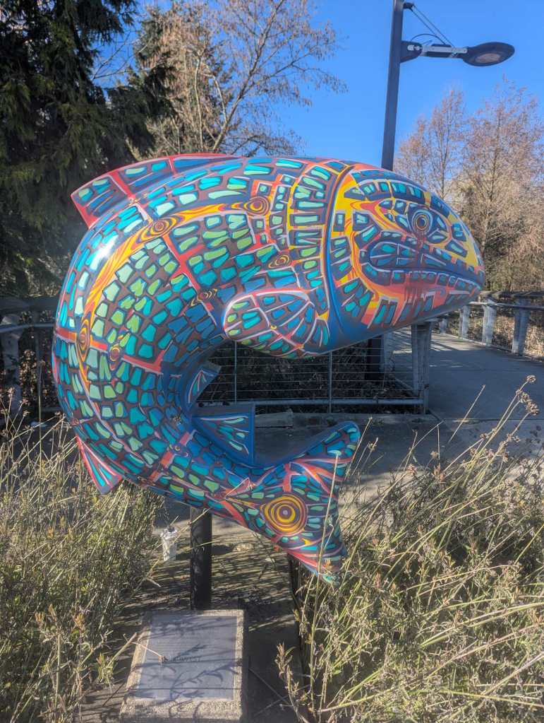 Eine Fischstatue am Eingang eines Parks, die mit verschiedenen Blau- und Rottönen verziert wurde. Der Fisch hat einen grimmigen Gesichtsausdruck. Eine Fischstatue am Eingang eines Parks, die mit verschiedenen Blau- und Rottönen verziert wurde. Der Fisch hat einen grimmigen Gesichtsausdruck.