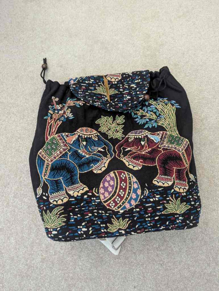 Ein bunter Rucksack mit zwei Elefanten, einem Ball und Fauna