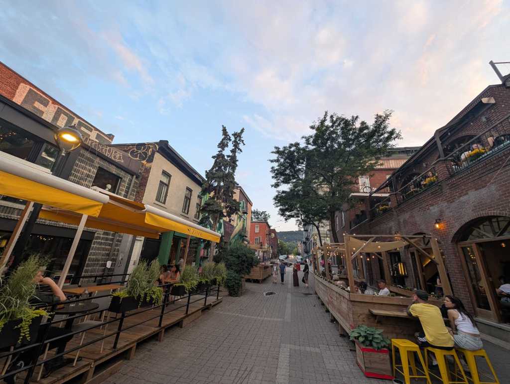 In einer Gasse säumen sich hölzerne Vorrichtungen für Restauranttische und -stühle.