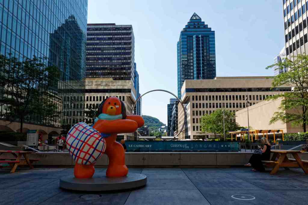 Die Skulptur eine orangen Cartoon-Hundes mit einer karierten Tasche.