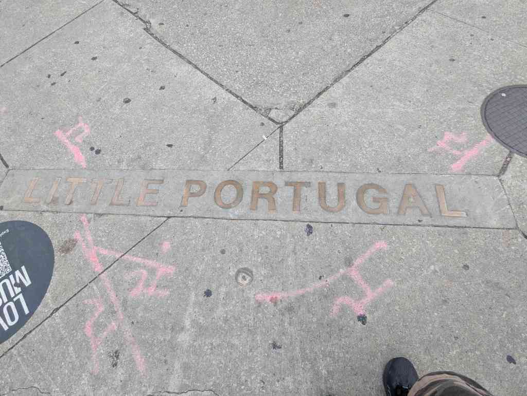 Auf einer Straße sind die Worte "Little Portugal" in den Asphalt eingraviert.