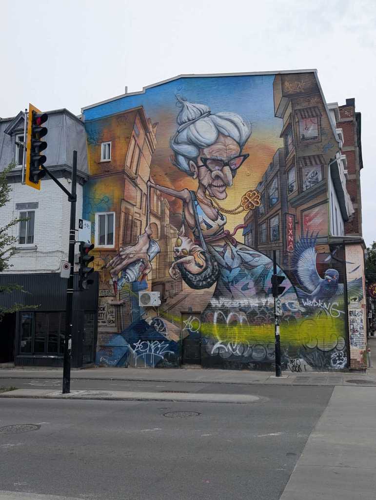 Mural einer Cartoon-Figur mit Dutt und schwarzer Brille, die eine Spraydose und einen kleinen Hund in einer Tasche dabeihat.